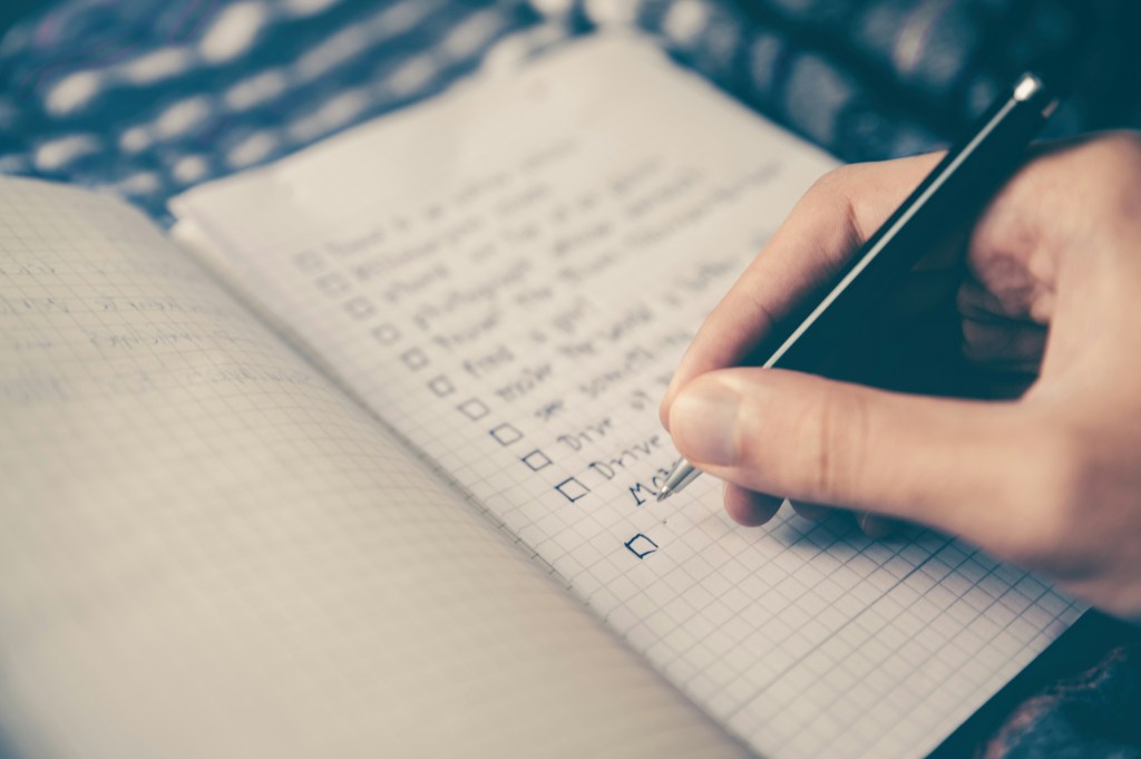 Female hand ticking off a list of items in a notebook